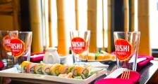 A plate of sushi and some Sushi Grand glasses on a table