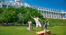 Family playing cornhole on lawn in front of Grand Hotel