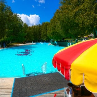 A yellow and red parasol in front of the pool