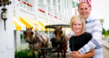 A couple posing in front of a horse carriage